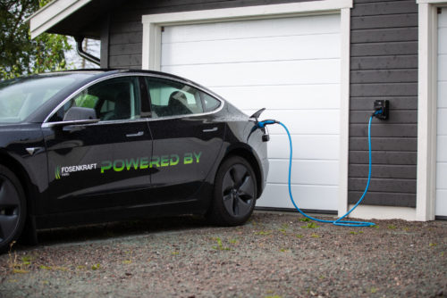 Elbillader på garasjevegg og sort elbil med Fosenkraft-logo